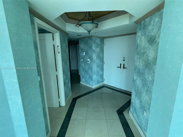 hall featuring light tile patterned floors, ornamental molding, a raised ceiling, and french doors