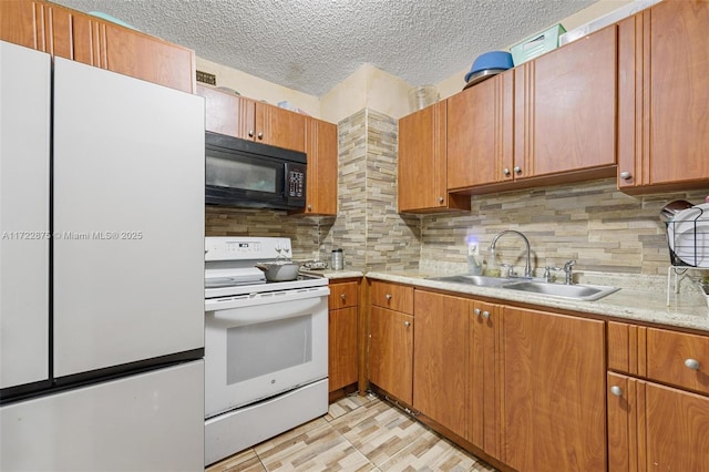 kitchen with a textured ceiling, white appliances, tasteful backsplash, and sink