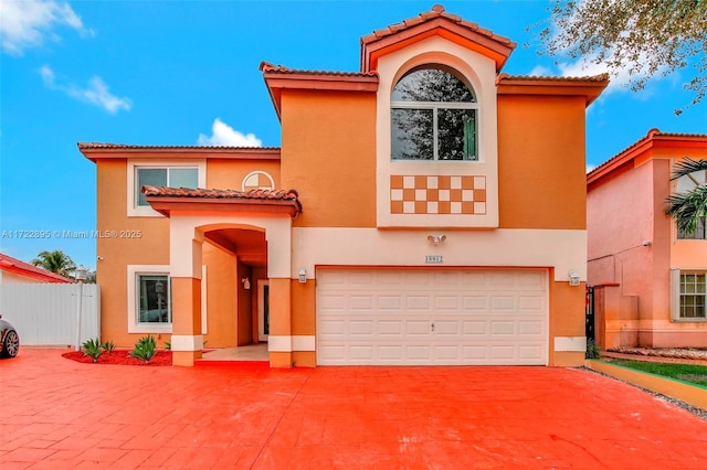 mediterranean / spanish-style house with a garage, fence, driveway, and stucco siding