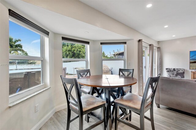 kitchen with light wood-type flooring, tasteful backsplash, light stone counters, and a wealth of natural light