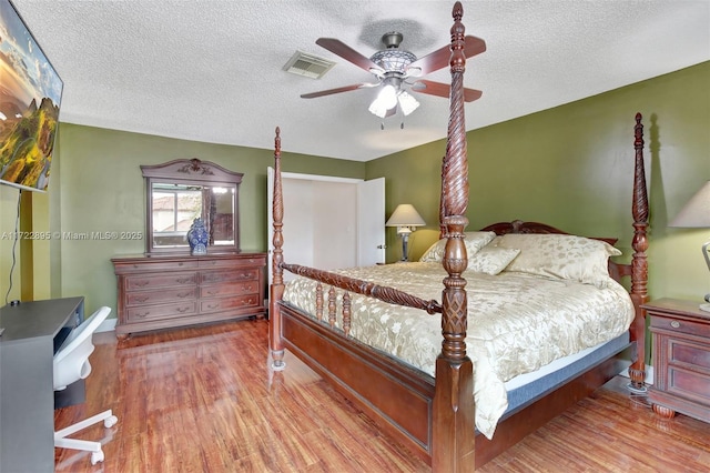 bedroom with wood-type flooring, a textured ceiling, and ceiling fan