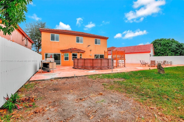 back of house featuring a lawn, a patio, and a pool