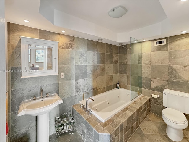 bathroom with a raised ceiling, toilet, and tile walls