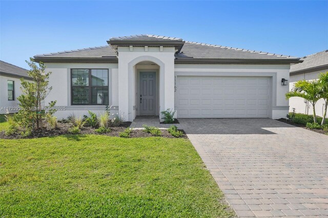 view of front facade featuring a tile roof, a front yard, driveway, and an attached garage