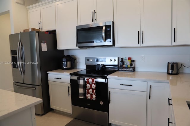 kitchen with light stone countertops, appliances with stainless steel finishes, light tile patterned floors, and white cabinetry