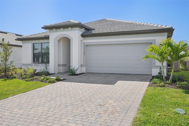 view of front of property featuring a tile roof, a garage, decorative driveway, and stucco siding