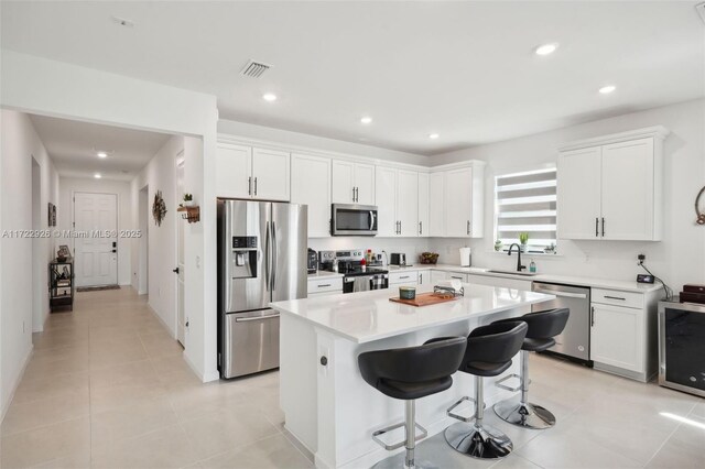 kitchen featuring light countertops, a kitchen island, visible vents, white cabinets, and appliances with stainless steel finishes
