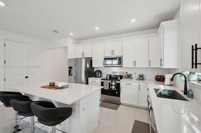 kitchen featuring a center island, white cabinetry, a sink, and stainless steel appliances