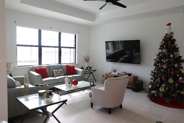 living room featuring a raised ceiling, light tile patterned floors, and ceiling fan