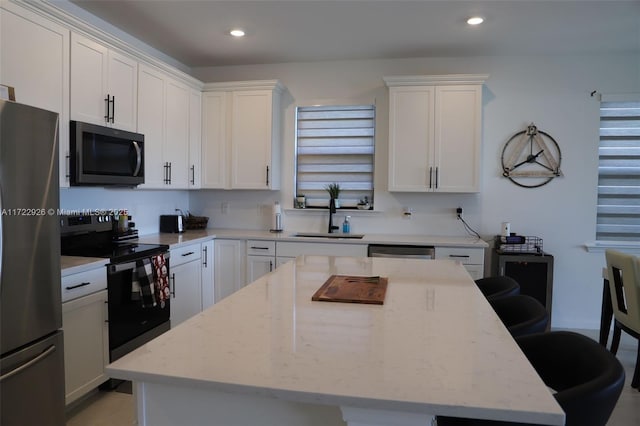 kitchen featuring white cabinetry, a center island, appliances with stainless steel finishes, and sink