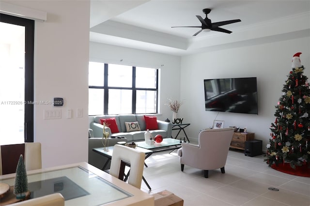 living room featuring crown molding, ceiling fan, a tray ceiling, and light tile patterned floors