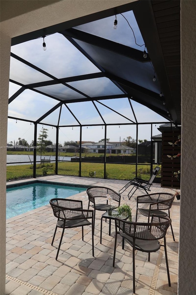 view of swimming pool featuring a water view, a lanai, and a patio