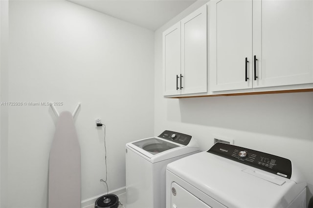 clothes washing area with cabinet space, washing machine and dryer, and baseboards