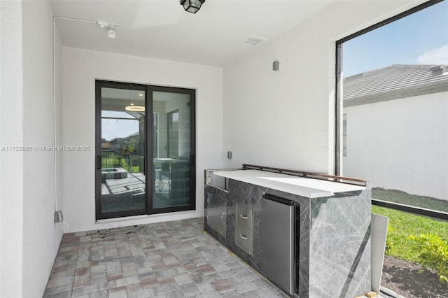 view of exterior entry with an outdoor kitchen, stucco siding, and a patio area