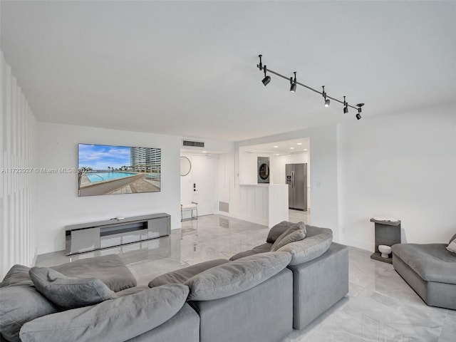 living room featuring rail lighting and stacked washer and dryer