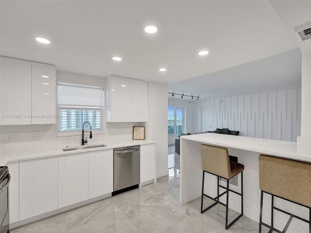 kitchen with white cabinets, sink, a wealth of natural light, appliances with stainless steel finishes, and a kitchen bar