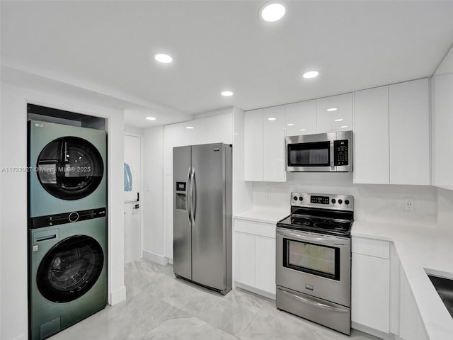 kitchen with sink, white cabinets, stainless steel appliances, and stacked washer / drying machine