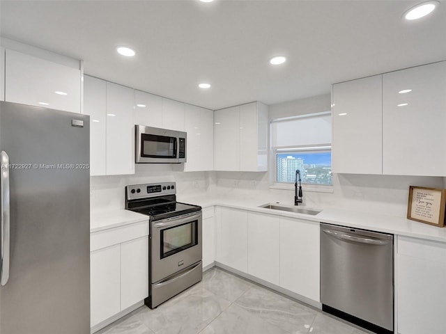 kitchen with decorative backsplash, stainless steel appliances, white cabinetry, and sink