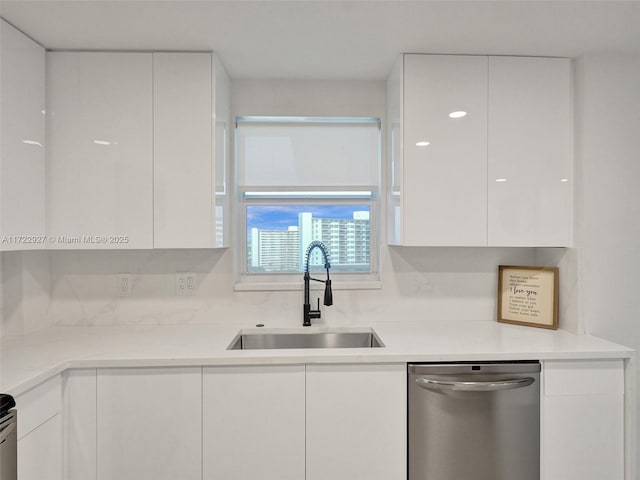 kitchen featuring decorative backsplash, sink, white cabinets, and stainless steel dishwasher