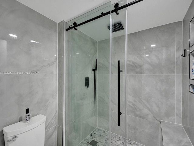 bathroom featuring toilet and a shower with shower door