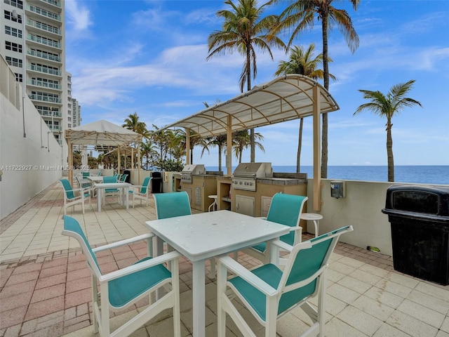 view of patio / terrace featuring a grill, a water view, and an outdoor kitchen