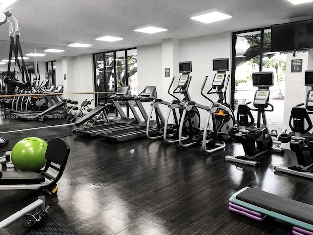 gym with floor to ceiling windows and a textured ceiling