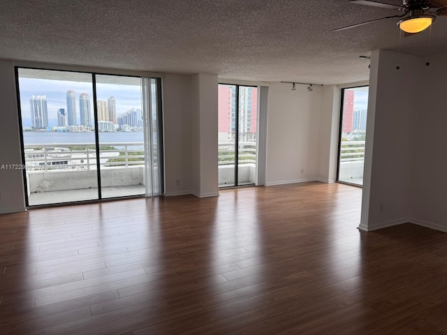 empty room featuring floor to ceiling windows, wood-type flooring, and ceiling fan