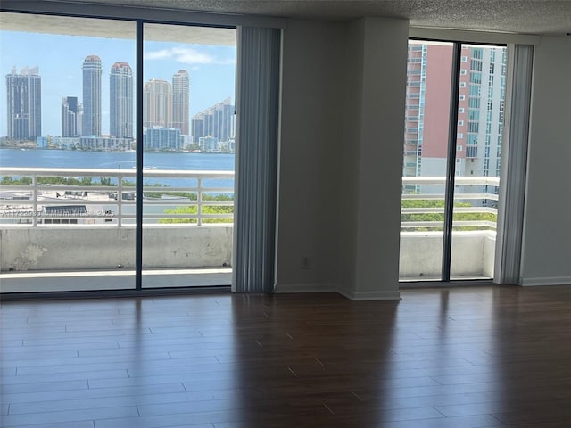 3300 NE 192nd St Unit 918, Aventura, FL 33180 - unfurnished room featuring dark wood-style flooring, a water view, a city view, baseboards, and floor to ceiling windows