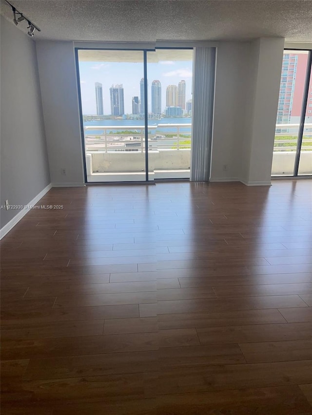 3300 NE 192nd St Unit 918, Aventura, FL 33180 - empty room featuring a textured ceiling, baseboards, expansive windows, and dark wood finished floors
