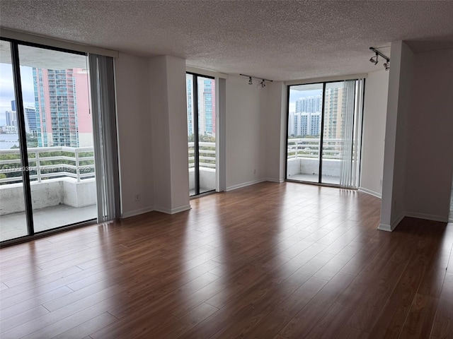 spare room featuring hardwood / wood-style flooring, floor to ceiling windows, and a healthy amount of sunlight