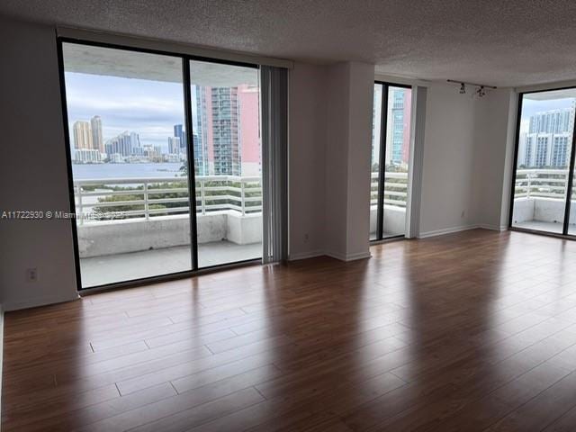 3300 NE 192nd St Unit 918, Aventura, FL 33180 - empty room with a view of city, a textured ceiling, floor to ceiling windows, rail lighting, and wood finished floors