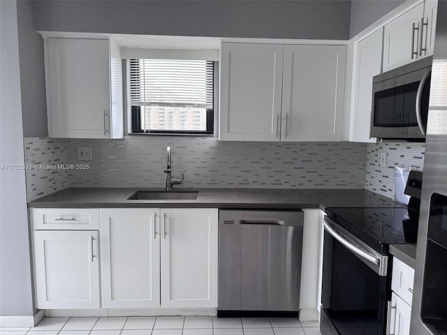 kitchen with sink, appliances with stainless steel finishes, white cabinets, light tile patterned flooring, and decorative backsplash