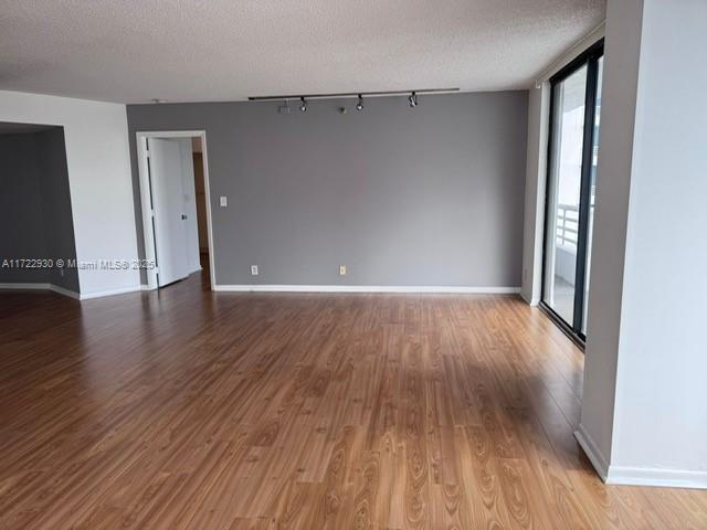 3300 NE 192nd St Unit 918, Aventura, FL 33180 - spare room with a textured ceiling, track lighting, wood finished floors, and baseboards
