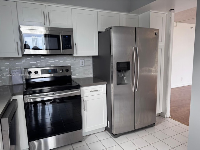 3300 NE 192nd St Unit 918, Aventura, FL 33180 - kitchen featuring decorative backsplash, white cabinets, appliances with stainless steel finishes, dark countertops, and light tile patterned flooring