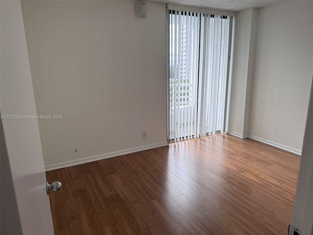 unfurnished room featuring hardwood / wood-style flooring and a textured ceiling