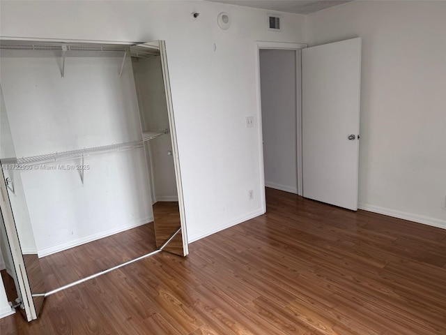 unfurnished bedroom with hardwood / wood-style flooring and a closet