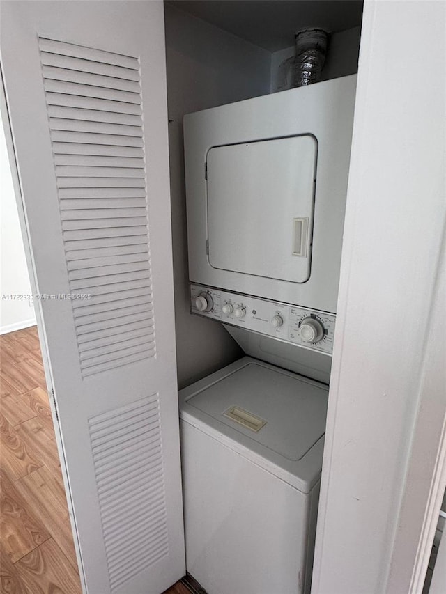 laundry room with hardwood / wood-style flooring and stacked washer and dryer