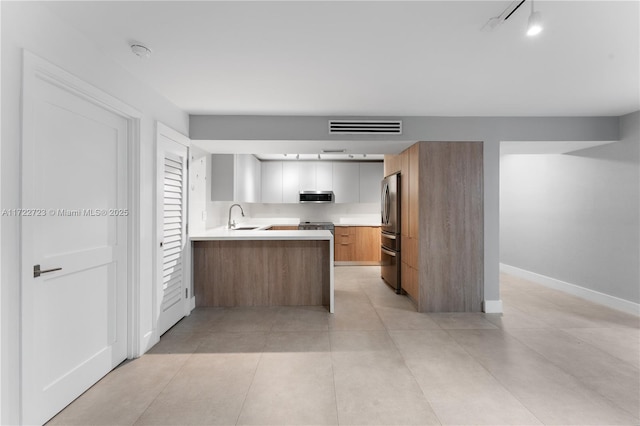 kitchen featuring kitchen peninsula, stainless steel appliances, sink, white cabinetry, and light tile patterned flooring