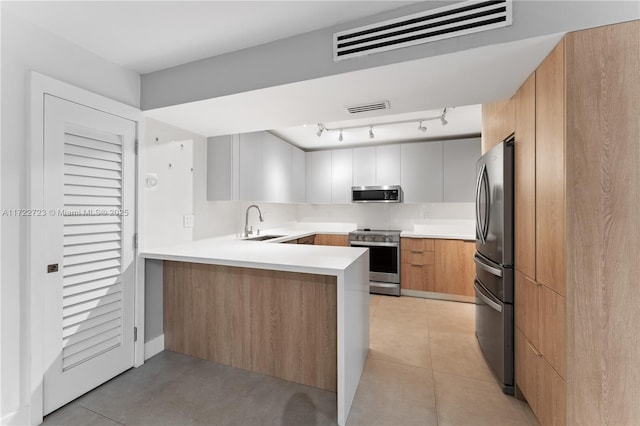 kitchen with kitchen peninsula, stainless steel appliances, sink, light tile patterned floors, and white cabinets