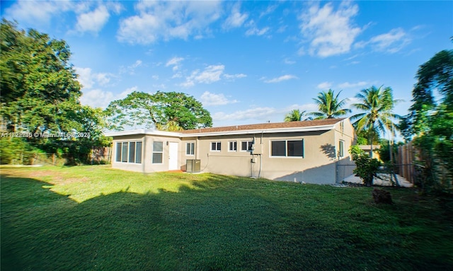 rear view of property with a yard and cooling unit