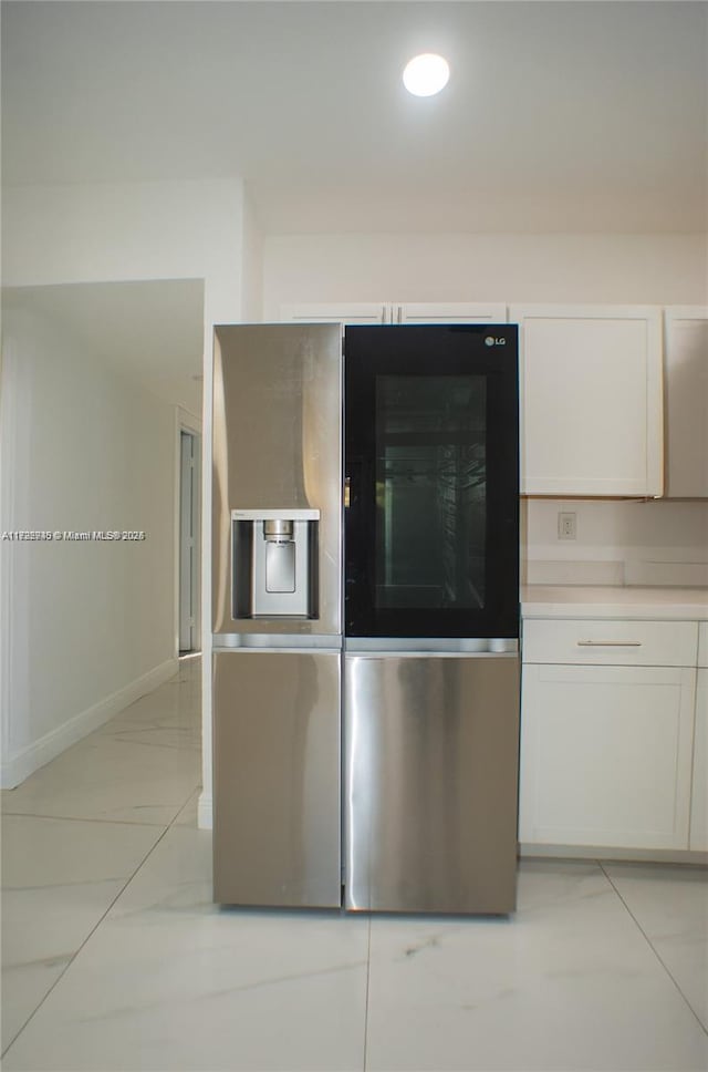 kitchen featuring stainless steel fridge and white cabinetry