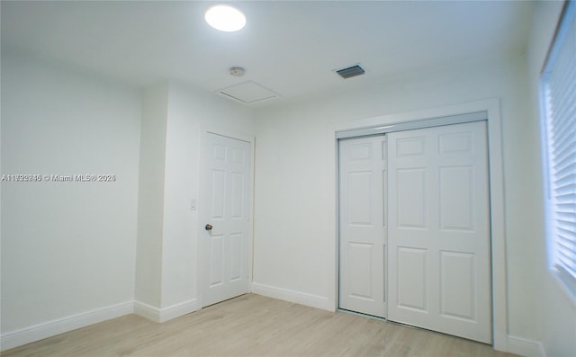 unfurnished bedroom with light wood-type flooring and a closet