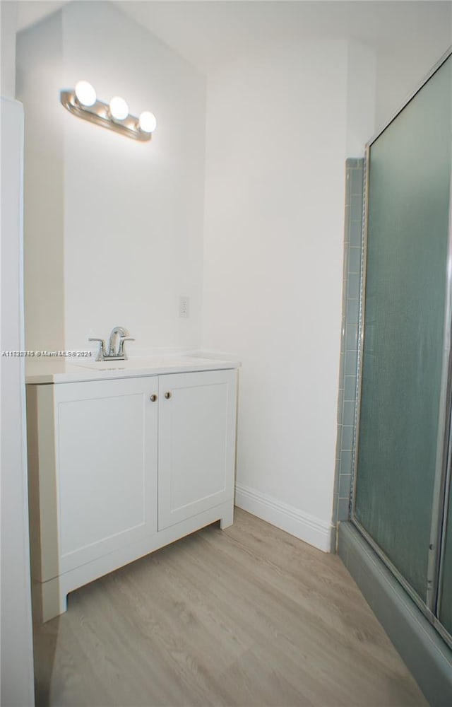 bathroom featuring hardwood / wood-style floors, a shower with shower door, and sink