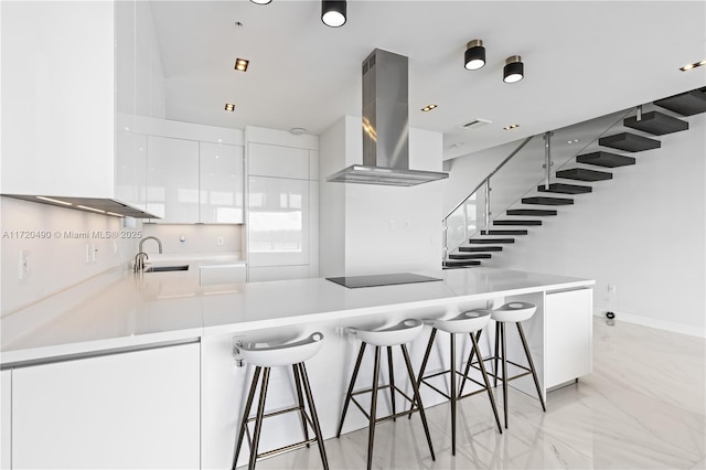 kitchen featuring range hood, a peninsula, a sink, black electric stovetop, and modern cabinets