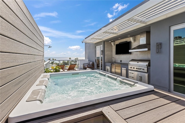 view of pool featuring an outdoor kitchen, a deck, sink, and grilling area