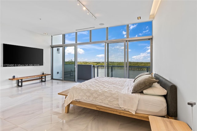 bedroom featuring a water view, access to exterior, and expansive windows