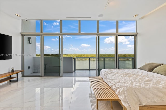 bedroom featuring expansive windows, a water view, and access to outside