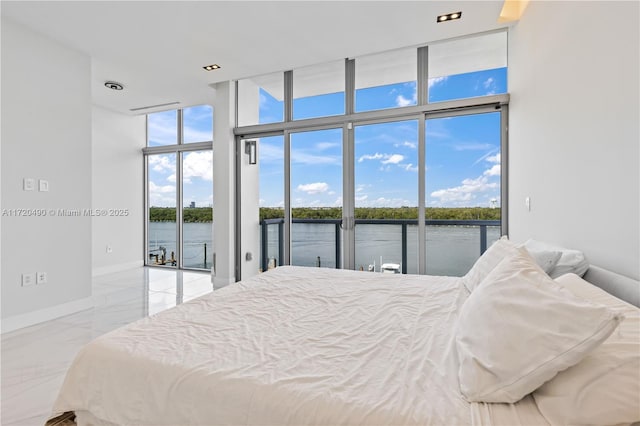 bedroom featuring access to exterior, floor to ceiling windows, and a water view