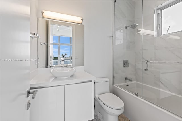 full bathroom featuring combined bath / shower with glass door, vanity, and toilet