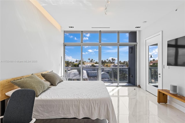 bedroom featuring multiple windows, rail lighting, access to outside, and floor to ceiling windows